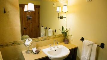 A bathroom with a sink, mirror, towel rack, and two wall-mounted lamps.