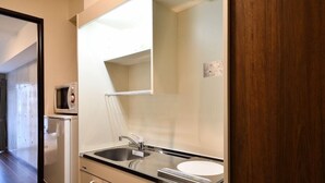 A kitchenette with a microwave, sink, and cabinets. - The Breakfast Hotel Porto Ishigaki (Ishigaki)