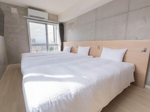 A hotel room with two beds, a large window, and an air conditioning unit. - The Breakfast Hotel Porto Ishigaki (Ishigaki)