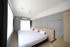 A modern hotel room with a large bed, a flat-screen TV, and a concrete accent wall. - The Breakfast Hotel Porto Ishigaki (Ishigaki)