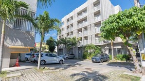 A multi-story building with balconies, parked cars, and palm trees. - The Breakfast Hotel Porto Ishigaki (Ishigaki)