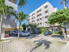 A multi-story building with balconies, parked cars, and palm trees. - The Breakfast Hotel Porto Ishigaki (Ishigaki)