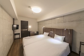 Habitación de hotel con una cama grande, un escritorio, una silla, un televisor montado en la pared y una puerta.