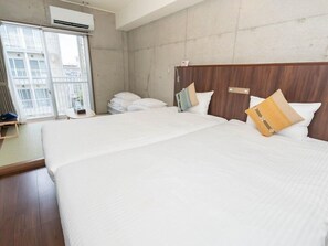 Habitación de hotel con una cama grande, cabecera de madera y ventana con vista a edificios.