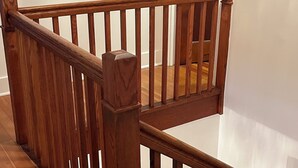 Een houten trap met een leuning en een houten deur op de achtergrond.