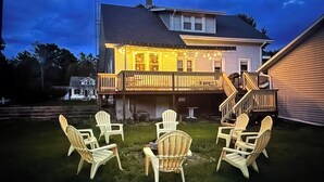 Een huis met een terras, een zitgedeelte buiten met stoelen, en een trap die naar het terras leidt.