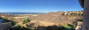 Eine Berglandschaft mit Blick auf das Meer, einem klaren Himmel und einigen Gebäuden in der Ferne.