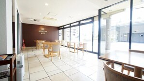 A hotel lobby with a reception desk, seating area, and large windows offering views of the outside. - Hotel Trend Mito (Mito)