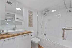 Un baño moderno con una bañera independiente, una ducha con mampara de vidrio y un inodoro blanco.