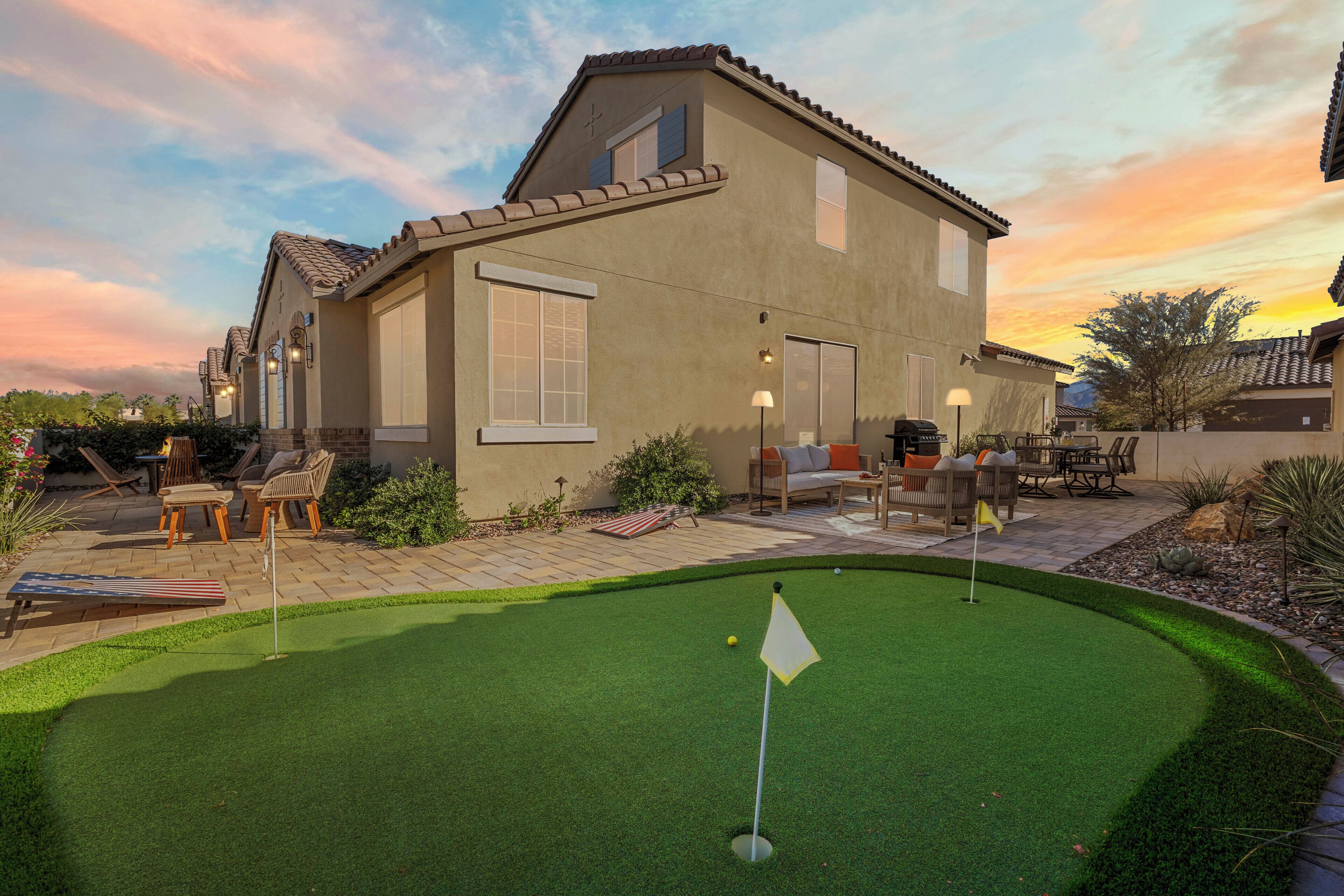 A house with a patio area featuring outdoor furniture and a putting green.