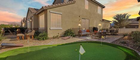 A house with a patio area featuring outdoor furniture and a putting green.