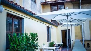 A courtyard with outdoor seating, a white umbrella, and potted plants.