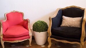 Two ornate armchairs, one red and one black, with a potted plant between them.