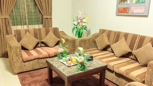 A living room with two sofas, a coffee table, and a floral arrangement. - Almuhaidb King Abdul Aziz (Riyadh)