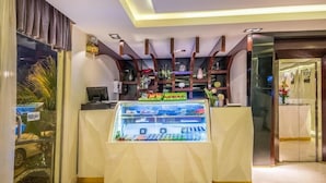 A hotel lobby with a reception desk, a glass display case with various items, and a wall-mounted shelf with decorative objects. - Almuhaidb King Abdul Aziz (Riyadh)