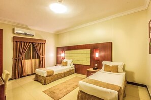 Quarto de hotel com duas camas, ar condicionado, cortinas e luminária fixada na parede.