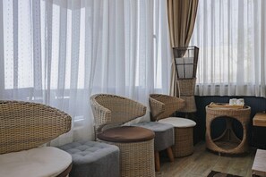 A room with wicker furniture, including chairs and ottomans, near a window with sheer curtains. - GO Walk Jiufen (New Taipei City)