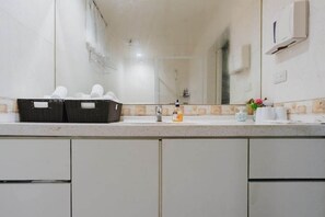 A bathroom with a mirror, a sink, a towel rack, and a basket of towels. - Go Walk Jiufen (New Taipei City)