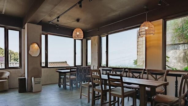 A spacious dining area with large windows, wooden tables and chairs, and hanging rattan lamps. - Go Walk Jiufen (New Taipei City)