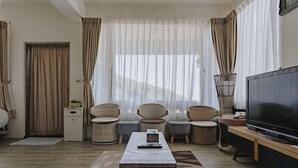 A living room with a television, wicker furniture, a coffee table, and sheer curtains. - Go Walk Jiufen (New Taipei City)