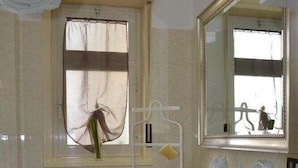 A bathroom with a toilet, sink, and window with a curtain. - Catania Aeroporto (Catania)