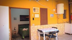 A room with a bed, a small table with chairs, a water heater, and a stone wall. - Catania Aeroporto (Catania)
