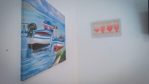 A room with a large painting of boats on the wall and a small heart-shaped decoration. - Catania Aeroporto (Catania)