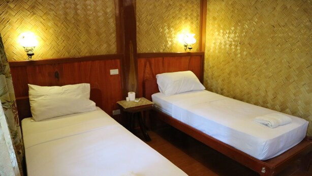 Two single beds with white linens, wooden headboards, and a nightstand with a lamp between them. - Villa Israel Ecopark El Nido by Cocotel Powered by Fave (El Nido)