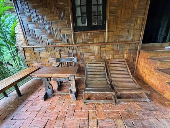 A rustic wooden hut with a thatched roof, a wooden bench, and a table. - Maesa Valley Garden Resort & Craft Village (Mae Rim)