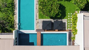A rooftop pool with two umbrellas, surrounded by greenery and a stone pathway. - Mirissa Beach Villa (Thalaramba)