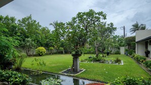A well-maintained garden with a pond, various plants, and a lawn. - Mirissa Beach Villa (Thalaramba)