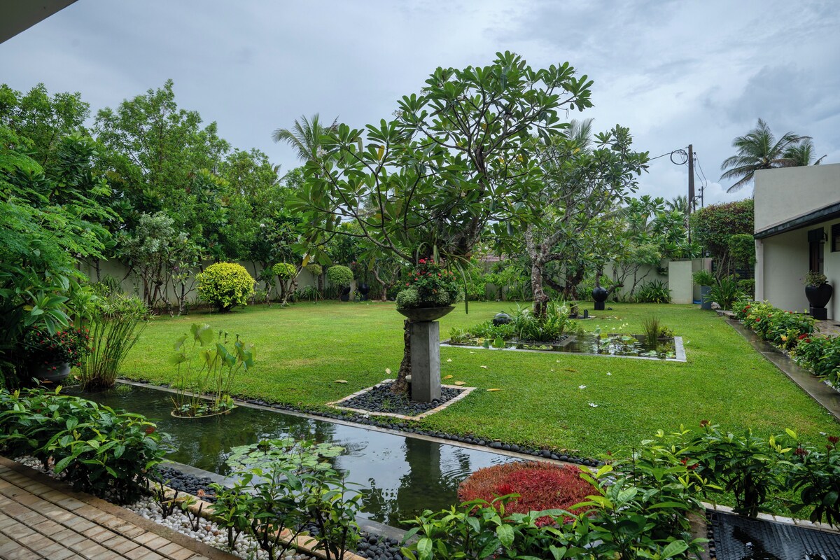 A well-maintained garden with a pond, various plants, and a lawn.