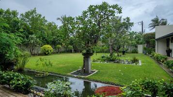A well-maintained garden with a pond, various plants, and a lawn.