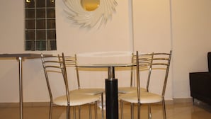 A dining area with a round table, four chairs, a black cylindrical object, and a decorative wall piece.
