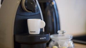 A coffee machine with a white cup labeled 'NESPRESSO' on its drip tray. - Suite Garibaldi Cosy Design Lyon Centre (Lyon)