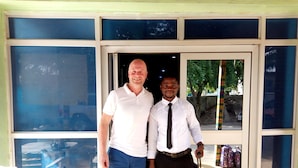 Two men standing at a doorway with a window and a view of the outside. - Haoxin Hotel (Accra)