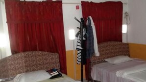 A room with two beds, red curtains, a wardrobe, and a wall-mounted light fixture. - Haoxin Hotel (Accra)