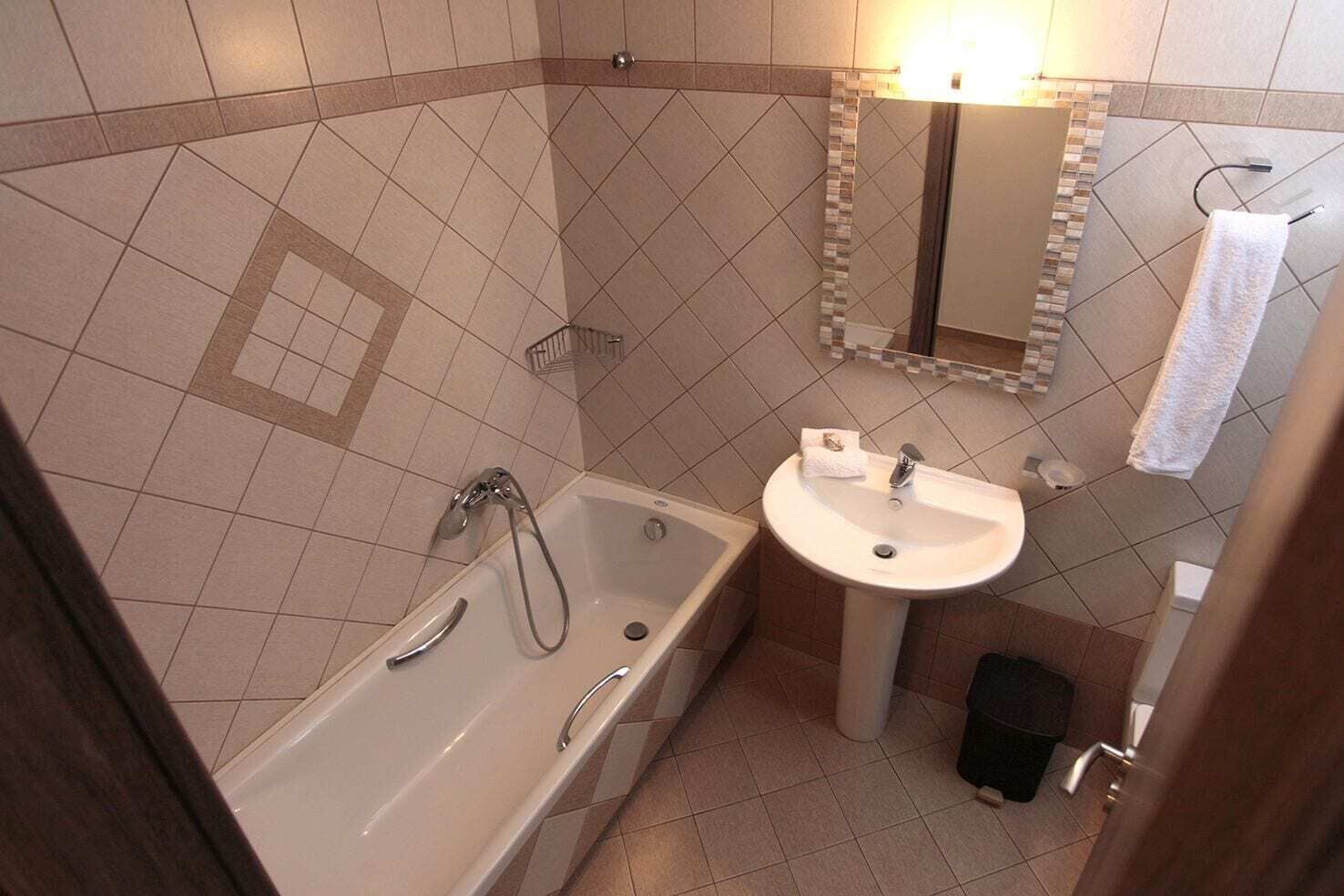 A bathroom with a bathtub, a sink, a mirror, and a towel rack.