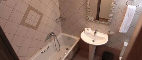 A bathroom with a bathtub, a sink, a mirror, and a towel rack.