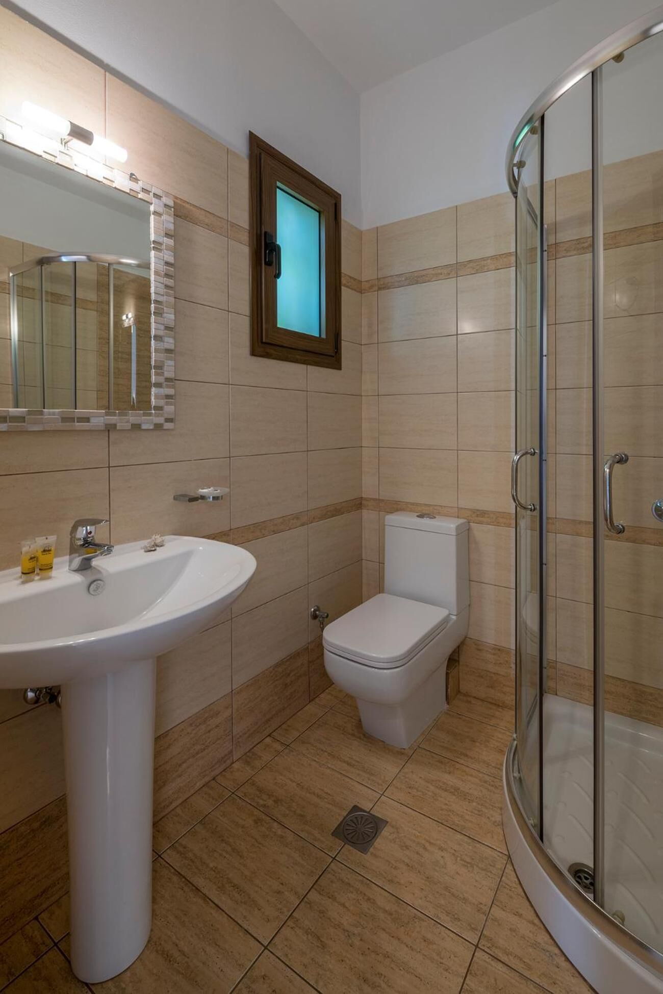 A bathroom with a sink, toilet, and glass shower enclosure.