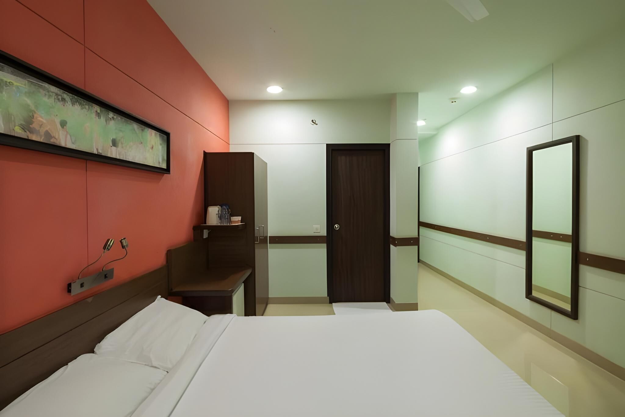 Una habitación de hotel con una cama, un armario, un escritorio y una puerta.