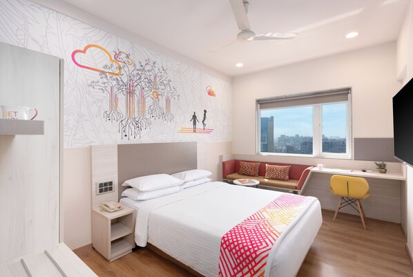 A modern hotel room with a large bed, a desk, and a window with a city view. - Ginger Andheri East (Mumbai)