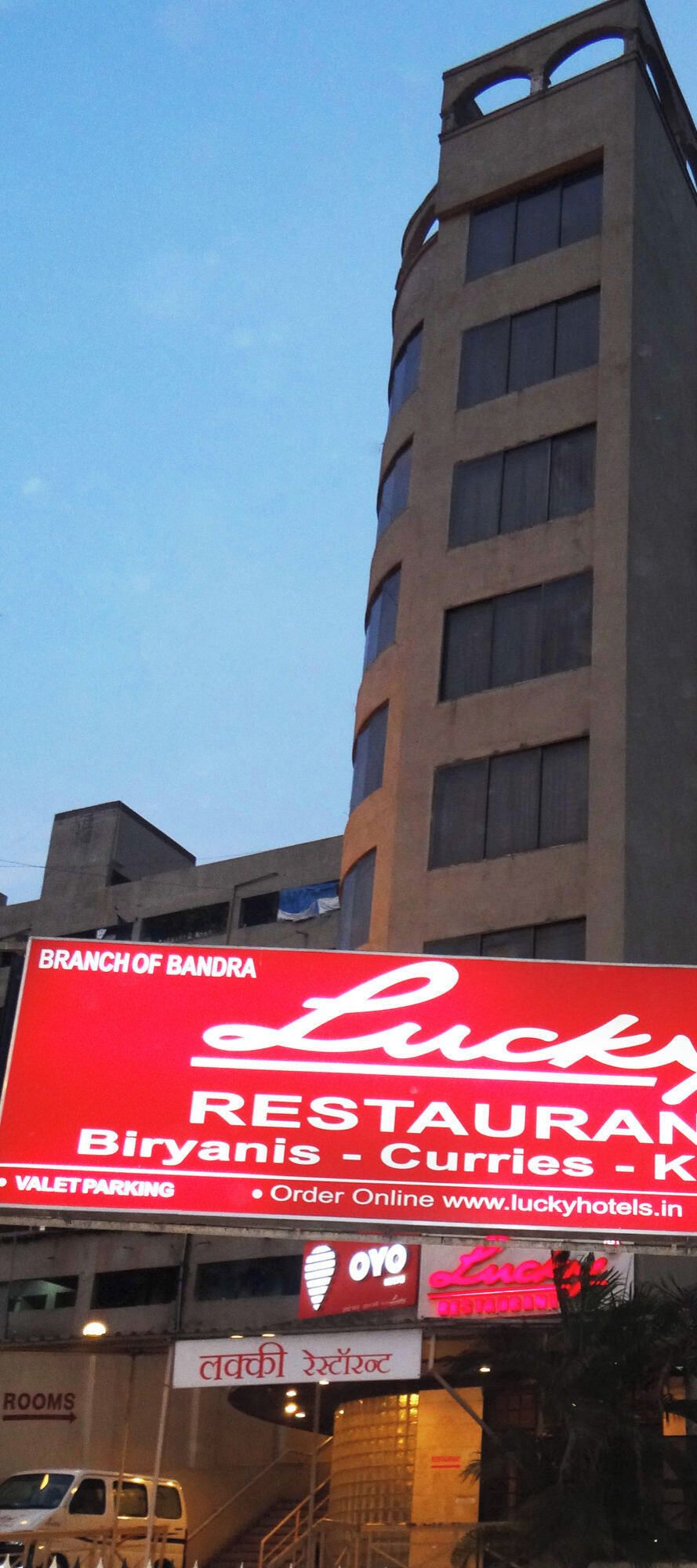 A building with a large red sign for a restaurant named 'Lucky Biryanis - Curries' and a sign for 'Branch of Bandra'.