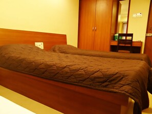 A double bed with a wooden headboard and a brown quilted bedspread. - Hotel Lucky (Mumbai)