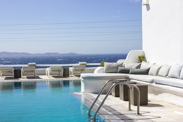 Uma área de piscina com vista para o mar e montanhas ao longe.