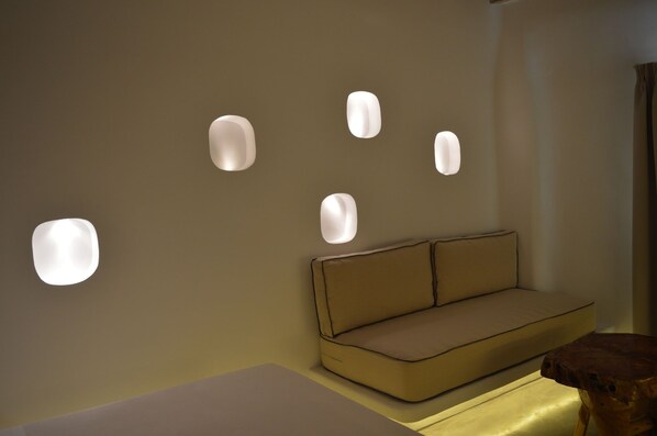 A modern room with a sofa and recessed wall lighting. - Flaskos Suites (Mykonos)