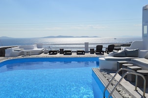 Zona de piscina con sillones de descanso y vista al mar.