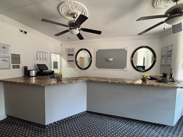 A reception area with a marble counter, two ceiling fans, a wall-mounted mirror, and a 'House Rules' sign. - THE Royal Alexandra (Blackpool)