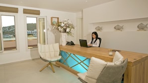 Ein Empfangsbereich mit einem Holztisch, zwei Stühlen, einem Laptop und einer Vase mit Blumen.