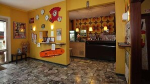 Un vestíbulo con suelo de piedra, un mostrador de recepción y una pared decorada con relojes y un cartel.